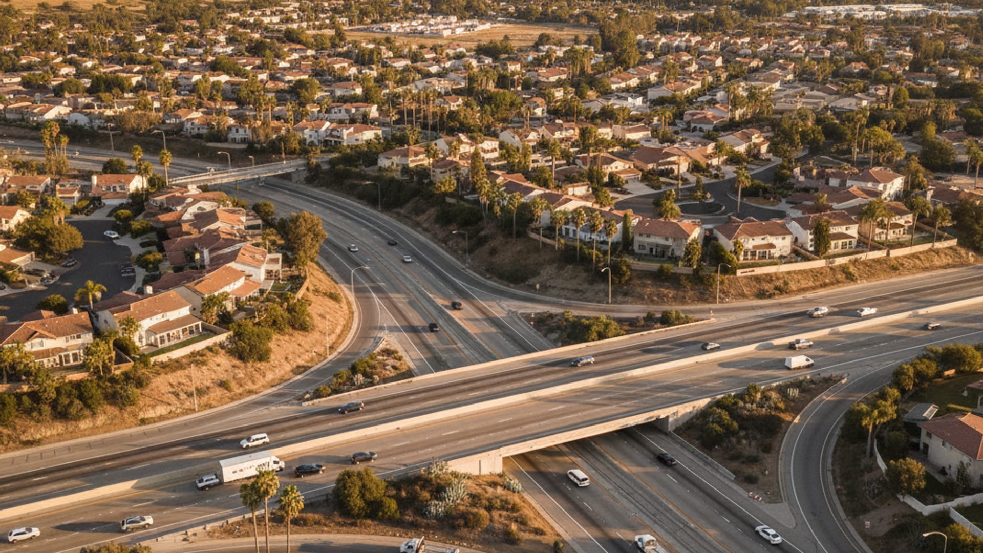 Elevated drone view of a New Orleans highway network with the Mississippi River, canals, and neighborhoods at golden hour